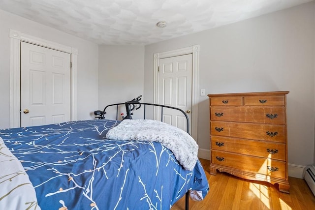 bedroom with wood finished floors and baseboard heating
