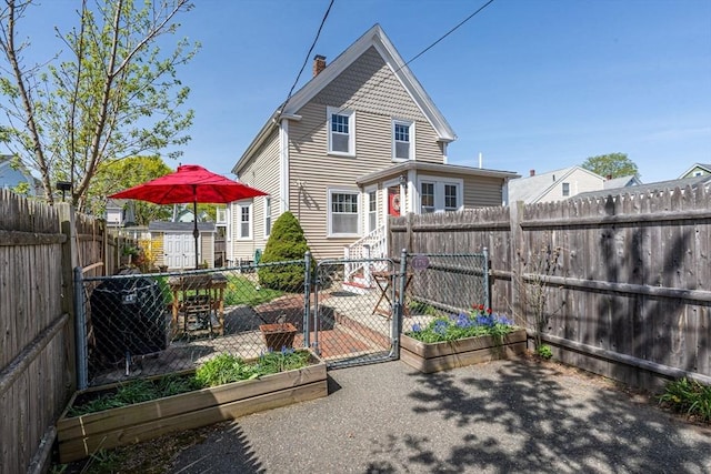 rear view of house featuring a fenced backyard, a gate, an outbuilding, and a storage shed