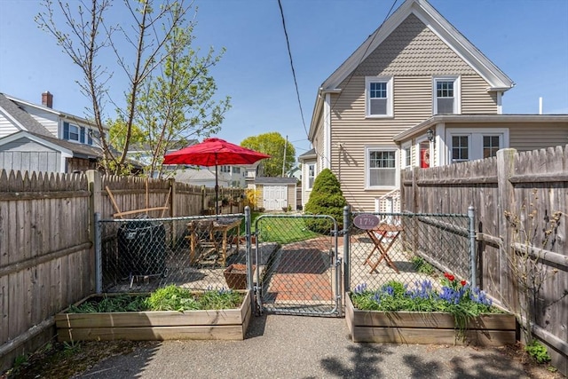 exterior space featuring an outdoor structure, a gate, a fenced backyard, and a storage unit