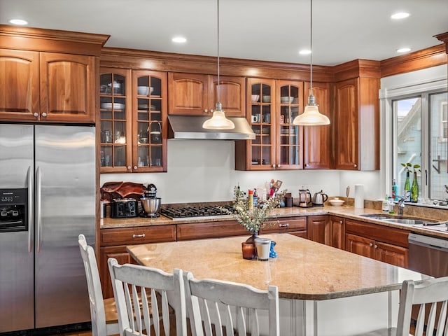 kitchen with range hood, appliances with stainless steel finishes, hanging light fixtures, and a breakfast bar