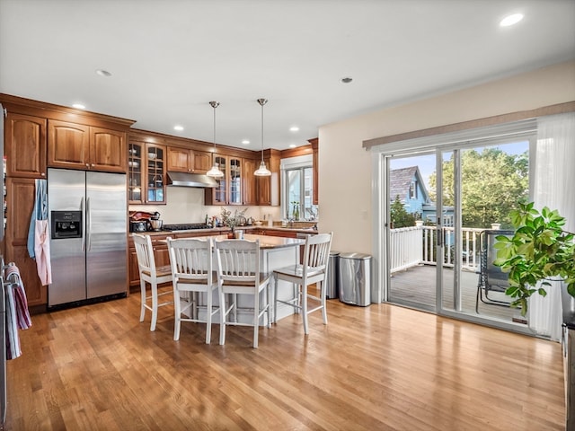 kitchen with pendant lighting, a kitchen island, appliances with stainless steel finishes, a breakfast bar area, and light hardwood / wood-style floors