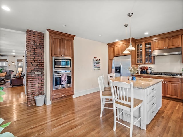 kitchen with light stone counters, stainless steel appliances, light hardwood / wood-style floors, and a kitchen island