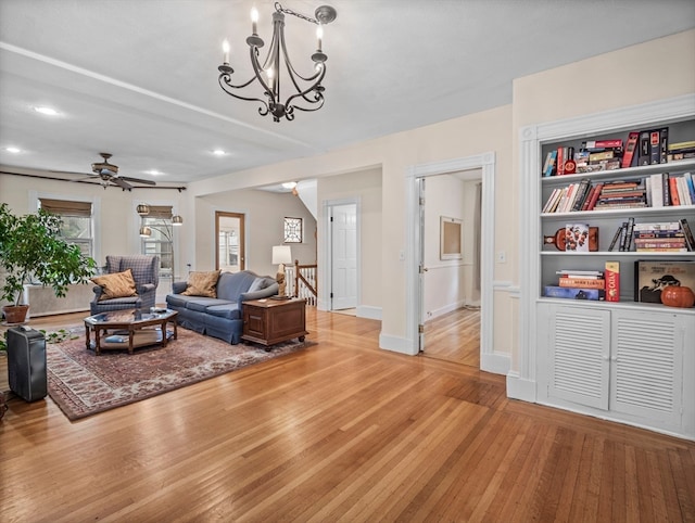 living room with ceiling fan with notable chandelier, light hardwood / wood-style floors, and built in features