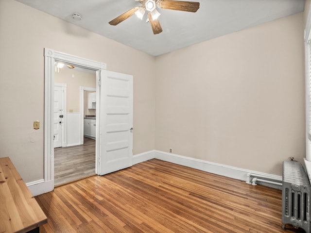 unfurnished bedroom with radiator, wood-type flooring, and ceiling fan