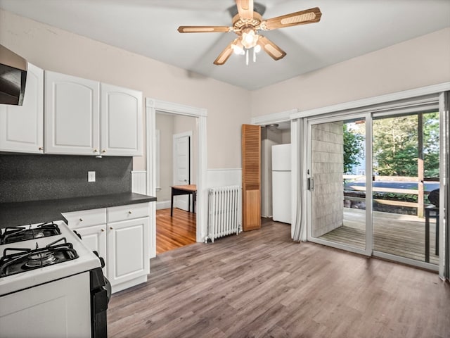 kitchen with white cabinetry, backsplash, light wood-type flooring, radiator, and ceiling fan