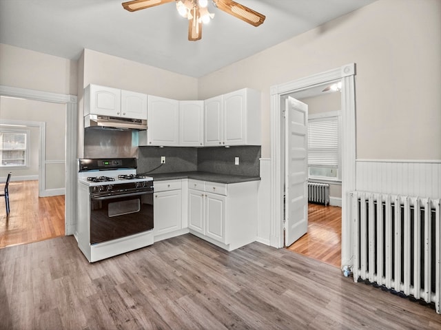 kitchen featuring light wood-type flooring, ceiling fan, radiator heating unit, and white gas stove