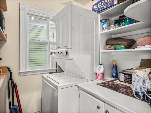 washroom featuring stacked washing maching and dryer and cabinets