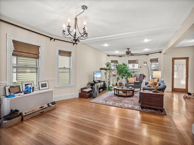 living room with ceiling fan with notable chandelier and light hardwood / wood-style floors