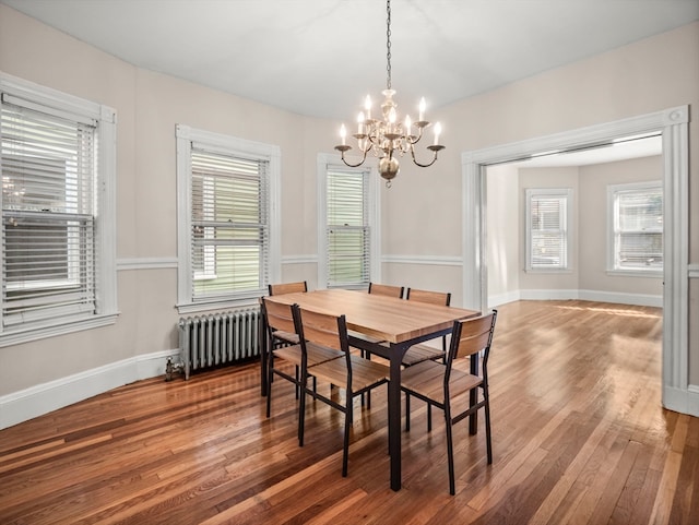 dining area with radiator heating unit, a notable chandelier, and hardwood / wood-style floors