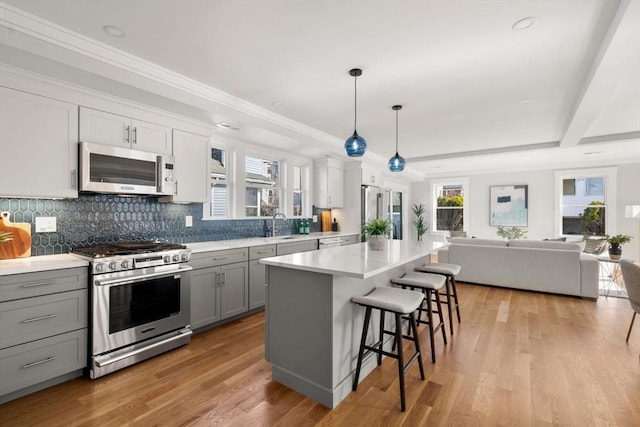 37-39 Governor Winthrop Rd, Somerville, MA 02145 - kitchen with a breakfast bar, open floor plan, backsplash, gray cabinetry, and stainless steel appliances