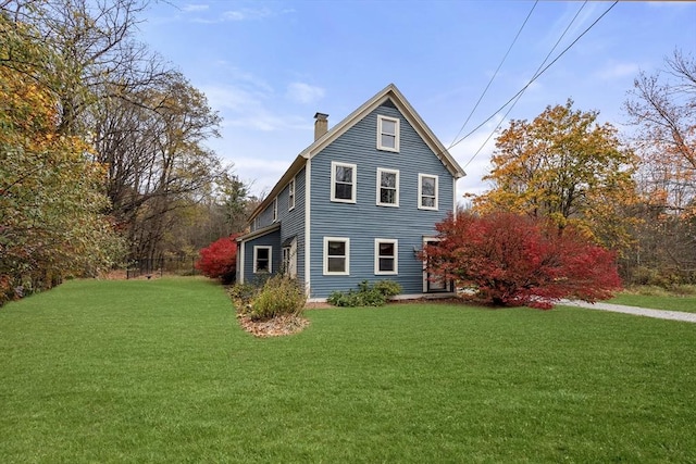 view of side of home with a chimney and a yard