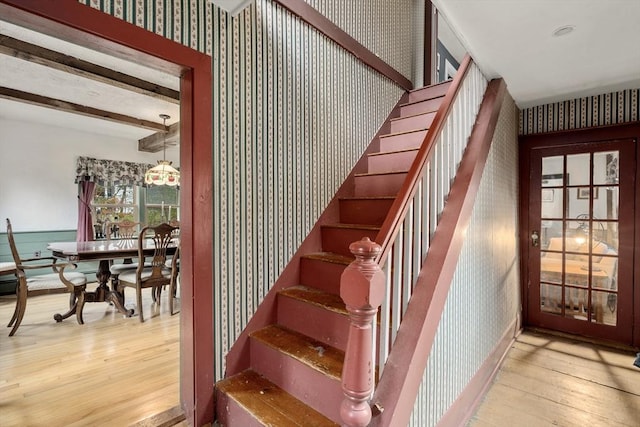 staircase featuring wood-type flooring and wallpapered walls