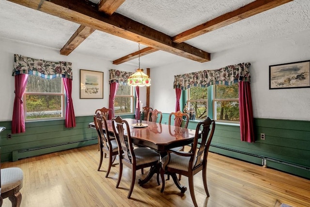 dining area with light wood-style floors, a textured ceiling, a wainscoted wall, and baseboard heating