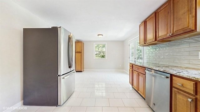 4 Gary Rd, Norton, MA 02766 - kitchen featuring appliances with stainless steel finishes, brown cabinets, tasteful backsplash, light stone counters, and baseboards