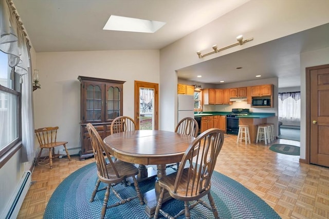 dining area with baseboard heating, lofted ceiling with skylight, sink, and light parquet floors