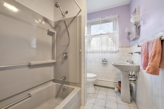 bathroom featuring a baseboard heating unit, tile patterned floors, tiled shower / bath, toilet, and tile walls