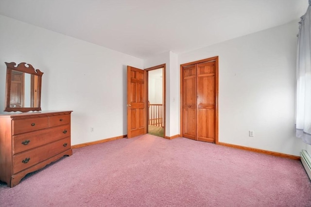 unfurnished bedroom with a baseboard heating unit, light colored carpet, and a closet