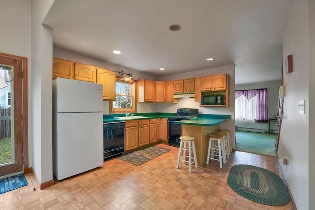 kitchen with a breakfast bar, sink, black appliances, a baseboard radiator, and light parquet flooring