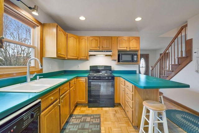 kitchen with a breakfast bar area, sink, light parquet flooring, and black appliances