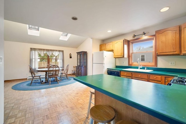 kitchen featuring a breakfast bar, sink, white refrigerator, black dishwasher, and light parquet flooring