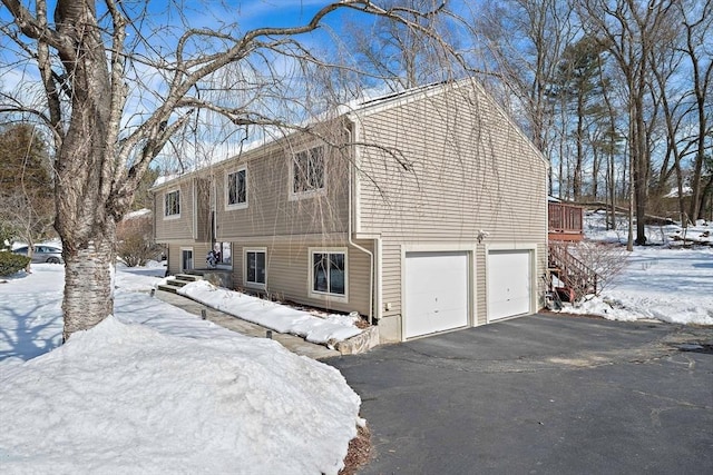 view of snow covered exterior with a garage and aphalt driveway