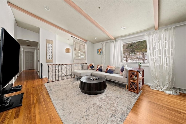 living room with vaulted ceiling with beams, a textured ceiling, wood finished floors, and baseboards