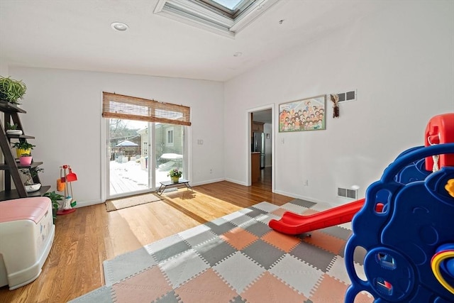 bedroom featuring a skylight, baseboards, visible vents, wood finished floors, and access to exterior