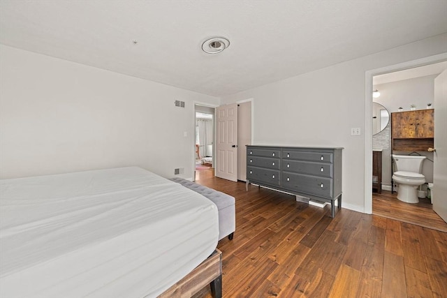 bedroom featuring dark wood-style floors, ensuite bathroom, visible vents, and baseboards