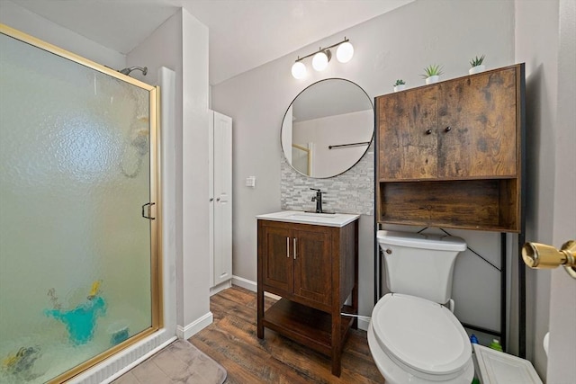 bathroom with a stall shower, toilet, vanity, and decorative backsplash