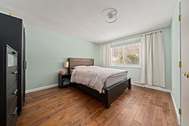 bedroom with a textured ceiling, wood finished floors, and baseboards