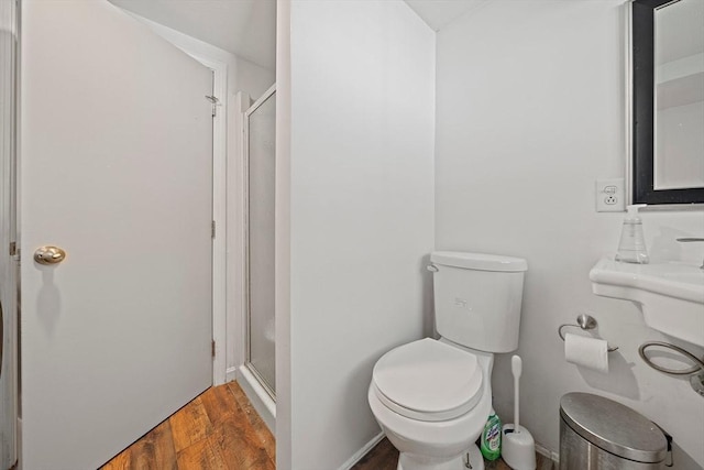 bathroom featuring a stall shower, toilet, and wood finished floors