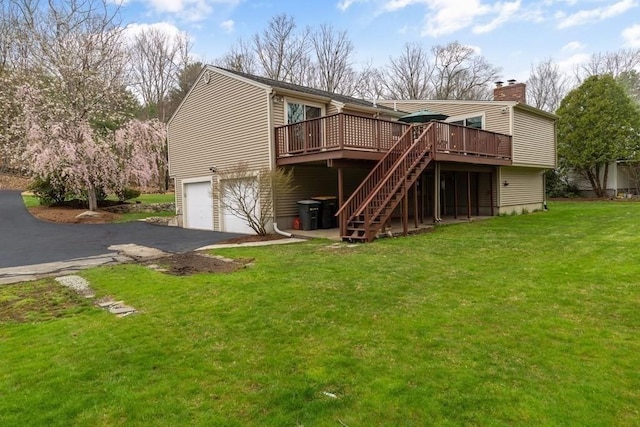 back of house featuring driveway, a lawn, an attached garage, stairs, and a deck