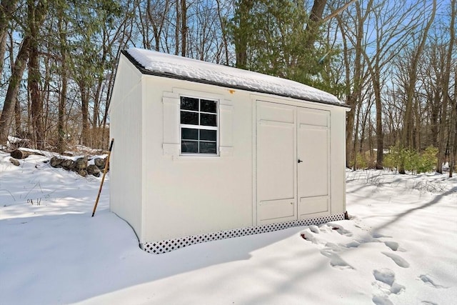 snow covered structure with an outdoor structure and a storage shed