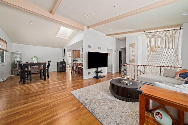 living room with vaulted ceiling with skylight, wood finished floors, and baseboards