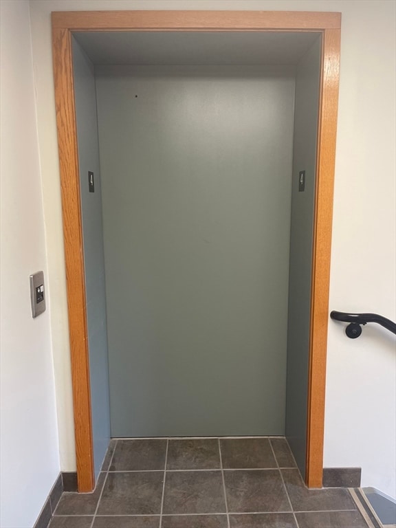 corridor with elevator and dark tile patterned flooring