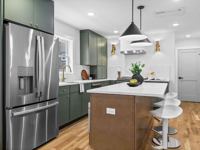 kitchen featuring a center island, green cabinets, a sink, light wood-type flooring, and stainless steel fridge