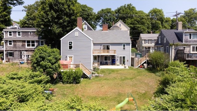 rear view of property with a chimney, stairs, and a yard