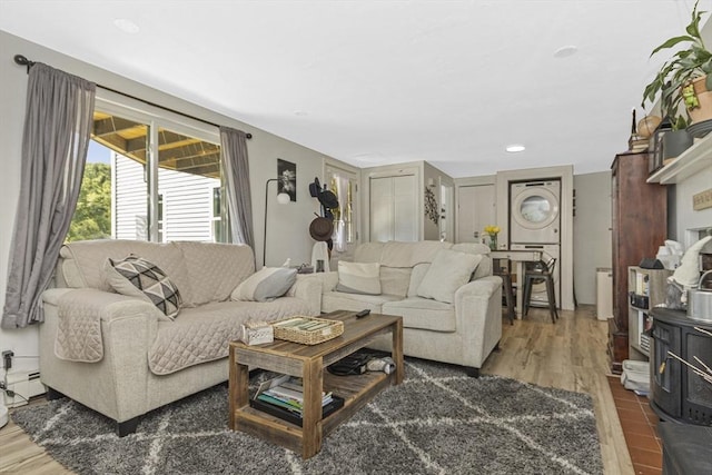 living room with recessed lighting, wood finished floors, a baseboard radiator, and stacked washing maching and dryer