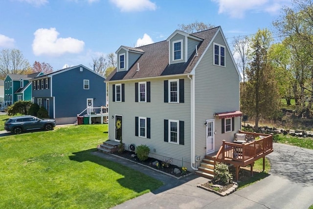 view of front of property featuring a wooden deck, a shingled roof, and a front yard