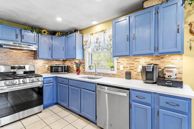 kitchen with a sink, blue cabinetry, under cabinet range hood, and stainless steel appliances