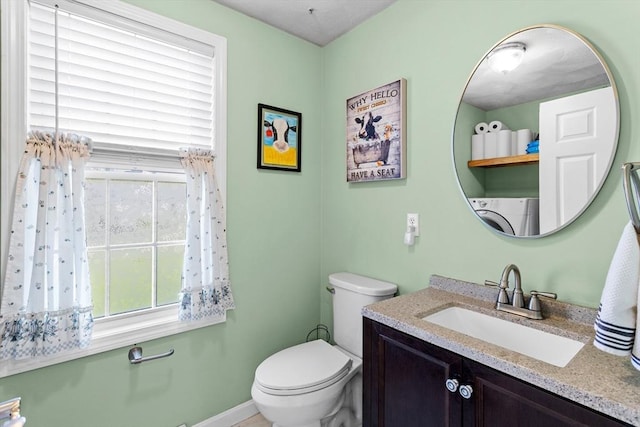 bathroom featuring vanity, washer / dryer, baseboards, and toilet