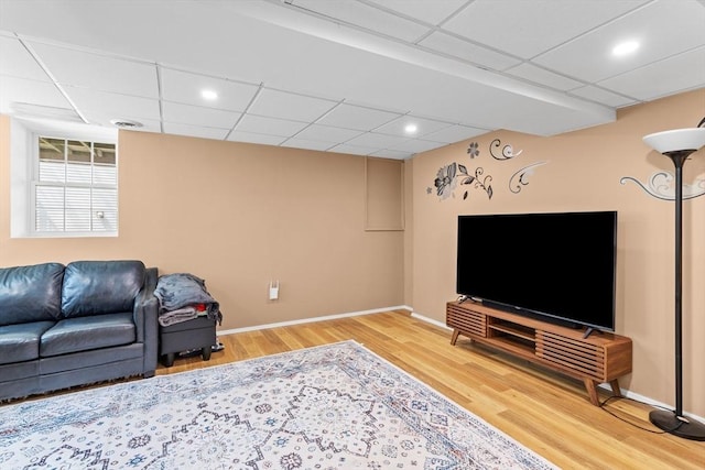 living area featuring wood finished floors, baseboards, and a drop ceiling