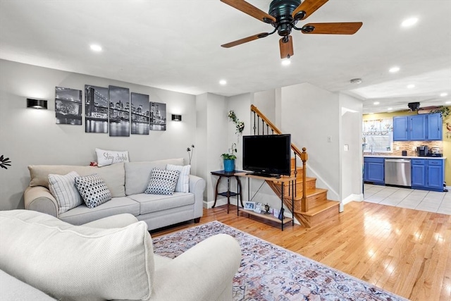 living room featuring stairway, ceiling fan, and light wood finished floors