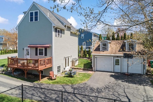 rear view of property with aphalt driveway, fence, roof with shingles, and a garage