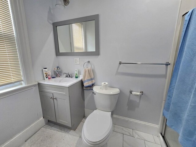 bathroom featuring baseboards, toilet, vanity, a shower with shower curtain, and marble finish flooring