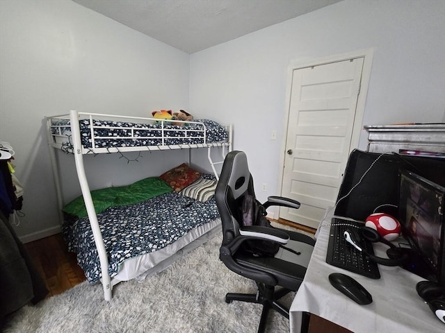 bedroom featuring wood finished floors, baseboards, and an office area