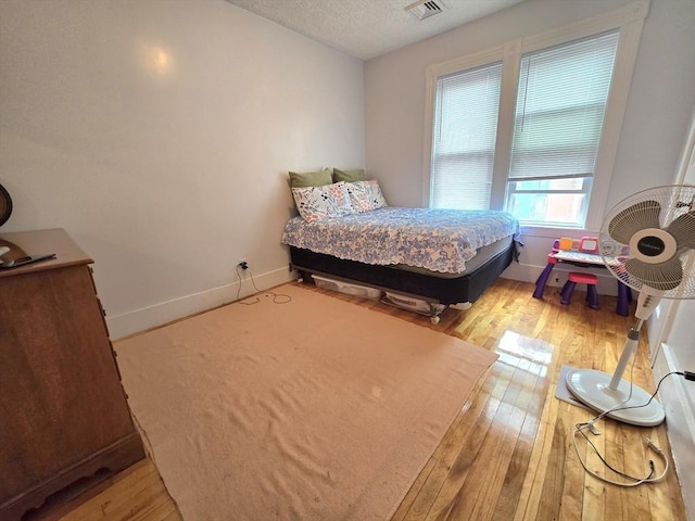 bedroom with wood-type flooring, baseboards, and a textured ceiling