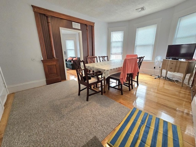 dining area with light wood finished floors, baseboards, and a textured ceiling