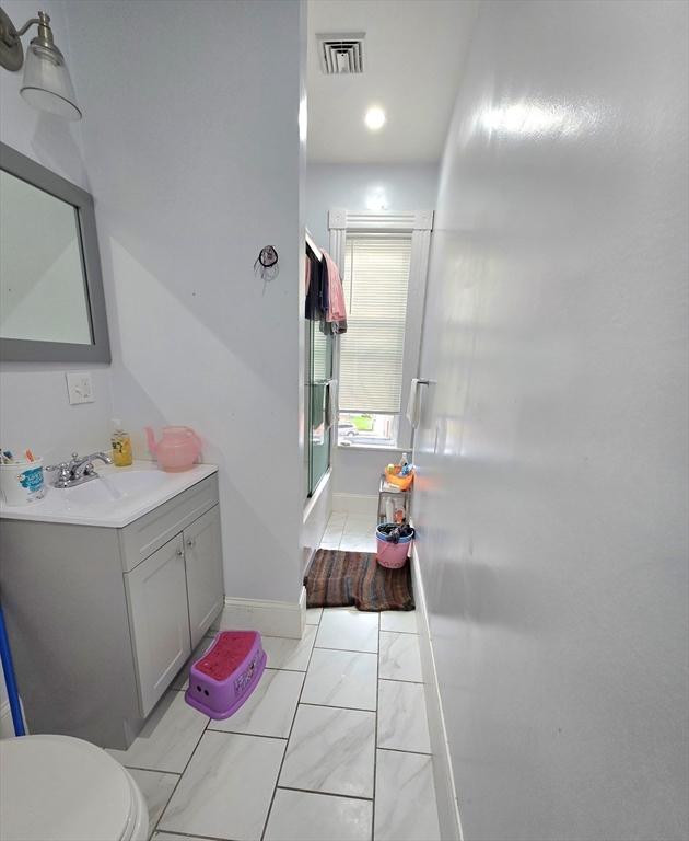 full bathroom featuring a shower with shower door, toilet, vanity, and baseboards