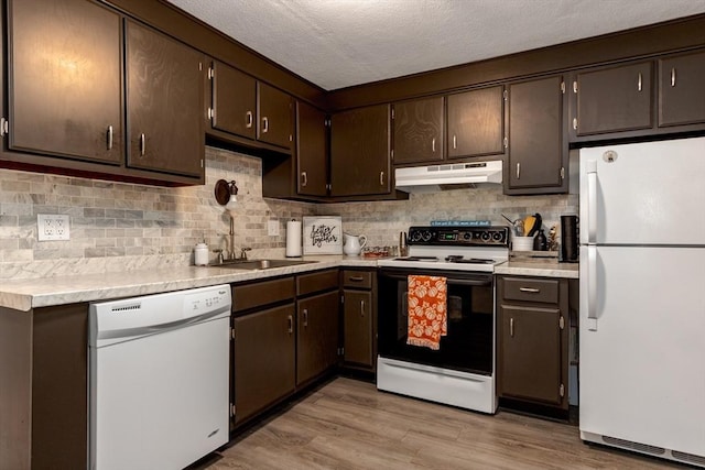 kitchen with white appliances, a textured ceiling, dark brown cabinets, light wood-type flooring, and sink